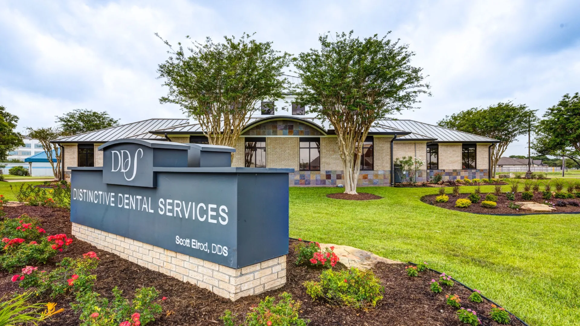 Distinctive Dental Services building with signage and landscaped garden under cloudy sky.