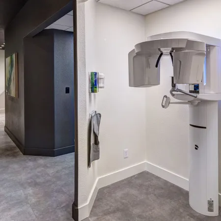 Modern dental office hallway with panoramic X-ray machine mounted on the wall in the corner.