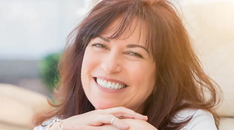 a woman smiling and holding her hands together